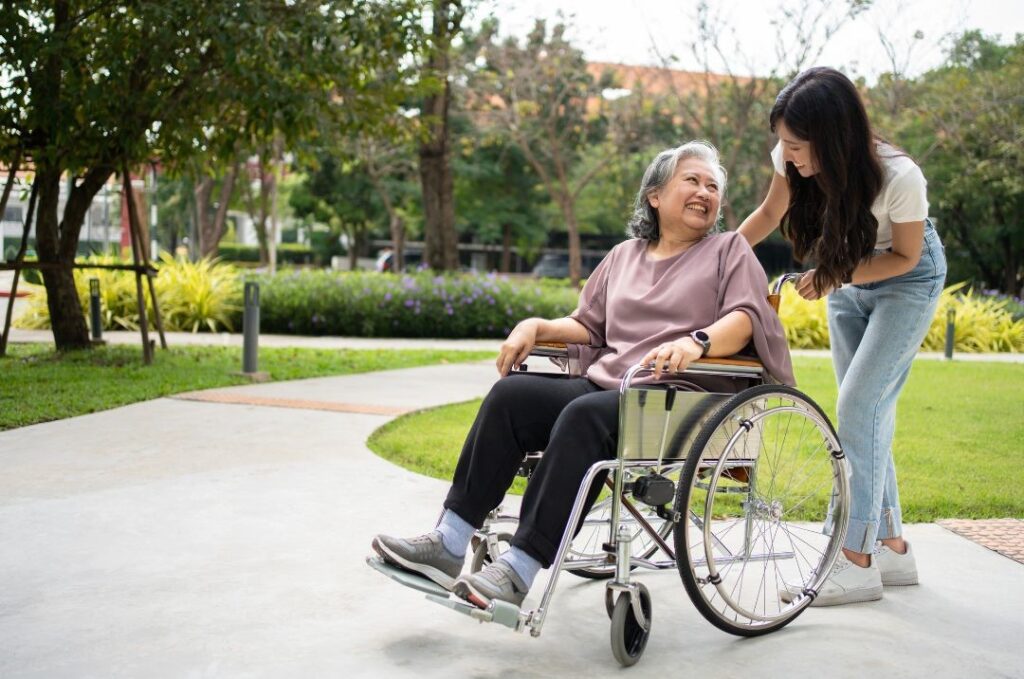 Une femme en fauteuil roulant discute en souriant avec la jeune femme qui la pousse
